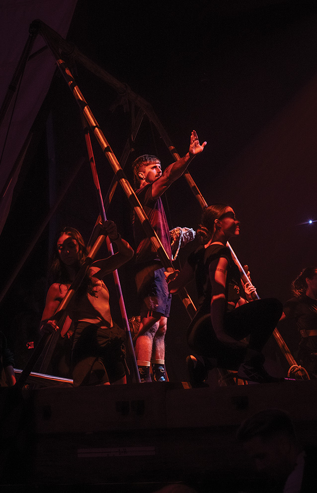 a group of people performing on stage with dramatic lighting