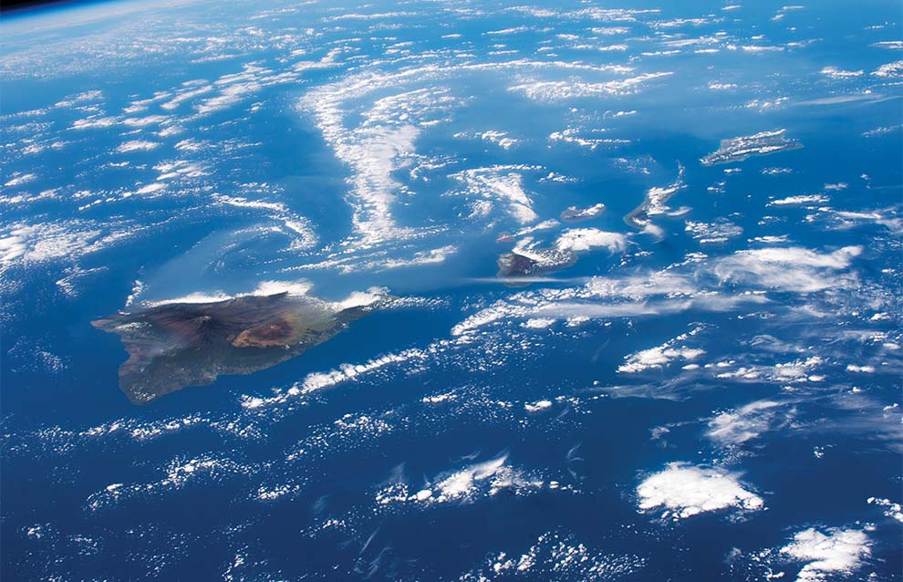 aerial photo of an island shore surrounded by water and clouds
